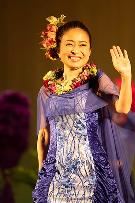 ステージに立って手を振る、アロヒラニのオーナー高橋正子